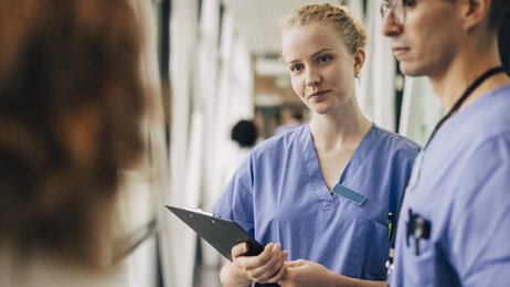 Bildet viser sykepleiere som lytter til en pasient.