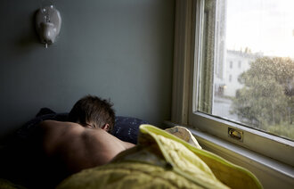 Bildet viser en ung mann som ligger i sengen