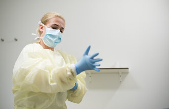 Bildet viser sykepleier Silvia Lopez, kledd i gul smittedrakt, som tar på seg hansker