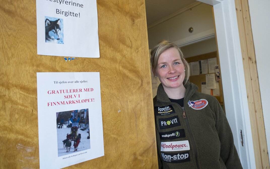 Bildet viser Birgitte Næss som står og kikker ut av kontordøra.