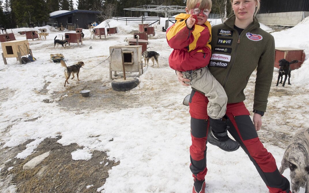 Birgitte går rundt i hundeg¨åreden med yngste sønn bærende på hofta