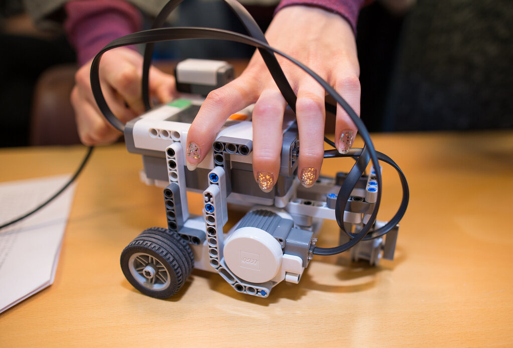 Bildet viser jentefingre som bygger en legorobot ved NTNU