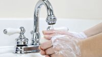Bildet viser et par hender innsmurt av såpe, som vaskes i springen