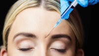 Woman receiving botox injection on her forehead in a examination room