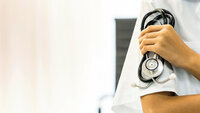 Beskåret bilde av kvinnelig helsepersonell med stetoskop i hånden.