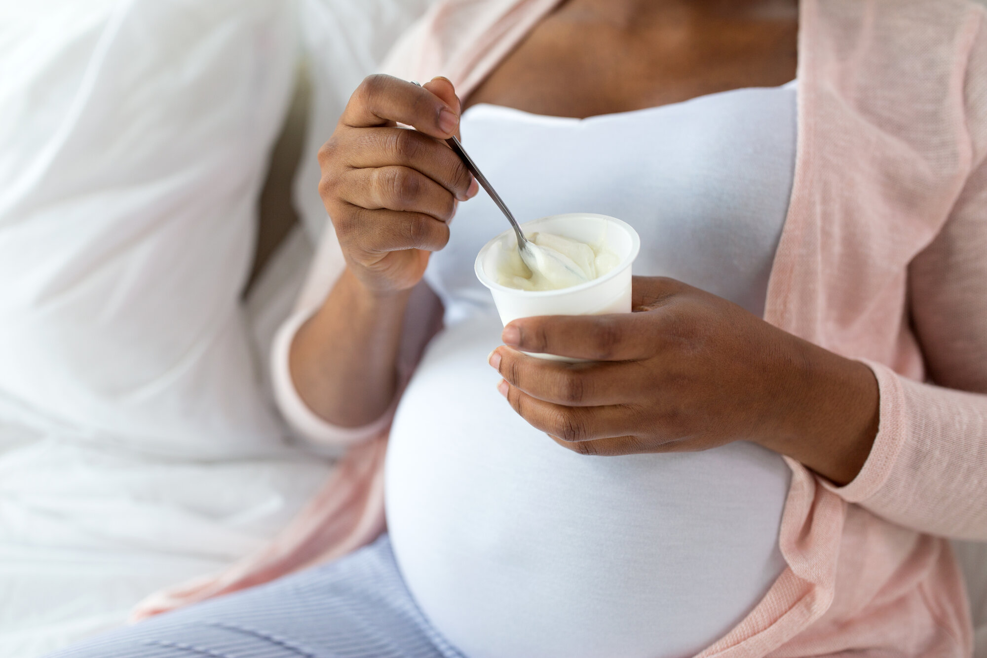 Bildet viser en gravid kvinne som spiser yoghurt