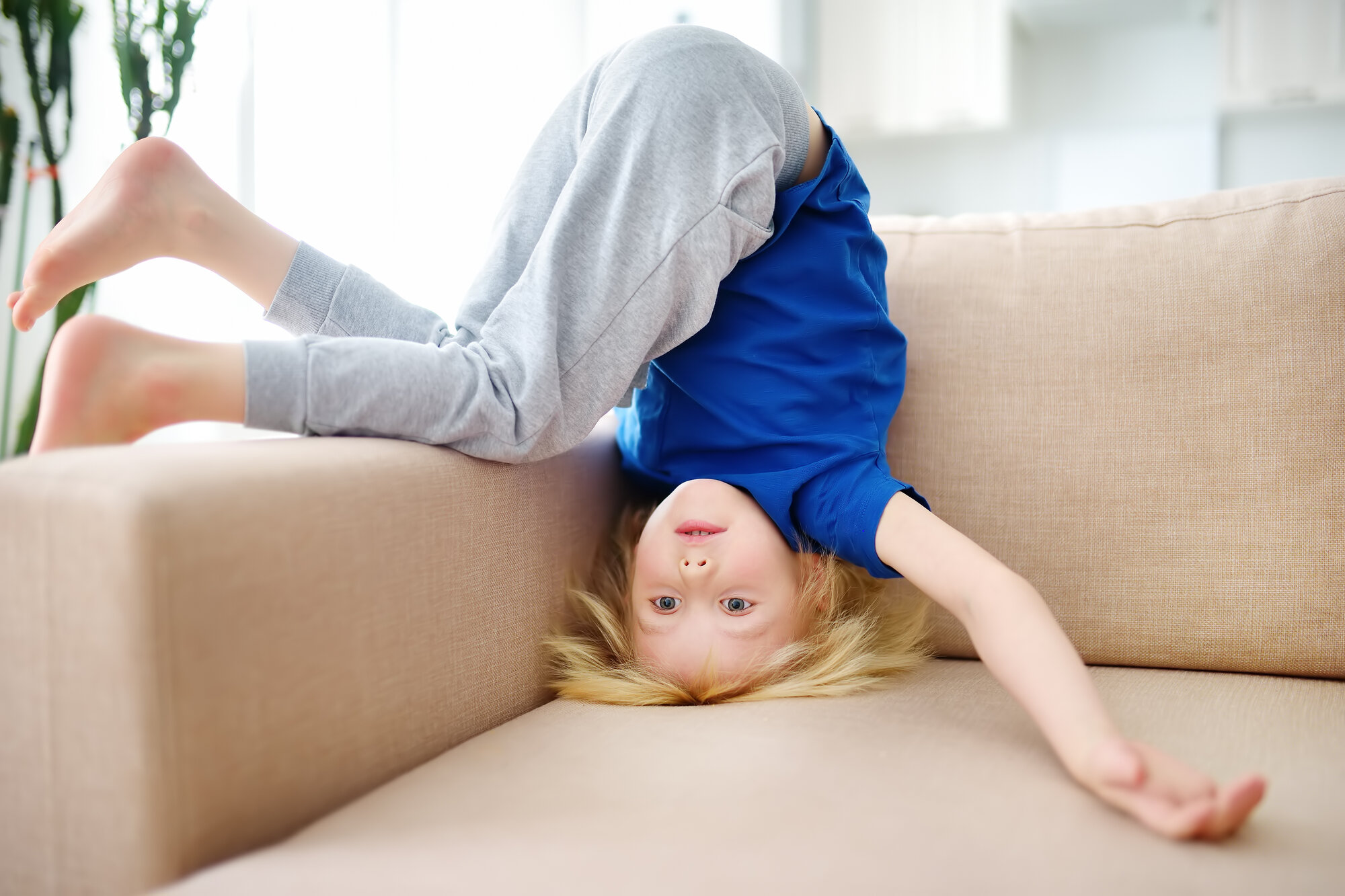 Et barn står på hodet i sofaen