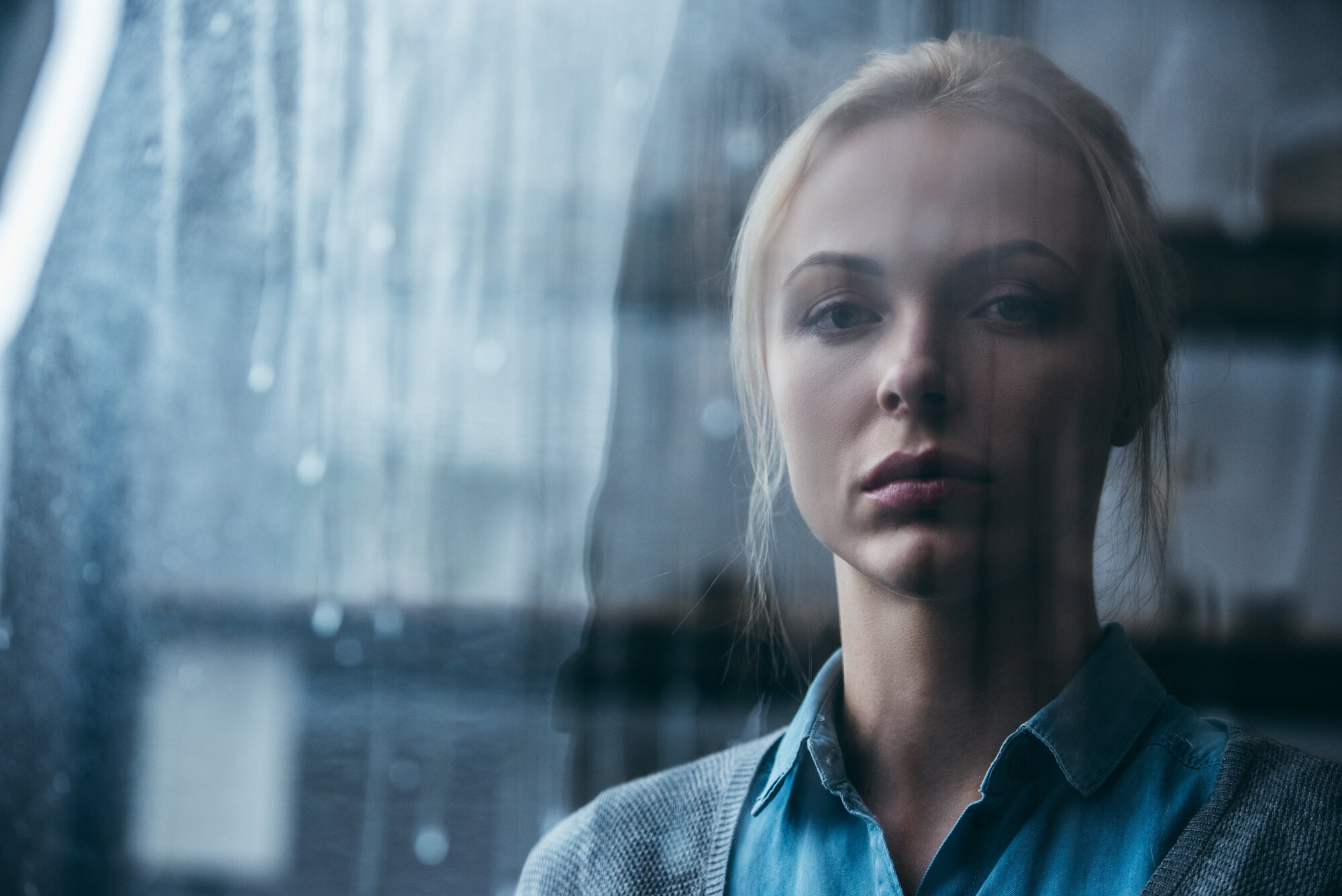 Bildet viser en trist kvinne som ser ut av et vindu. 