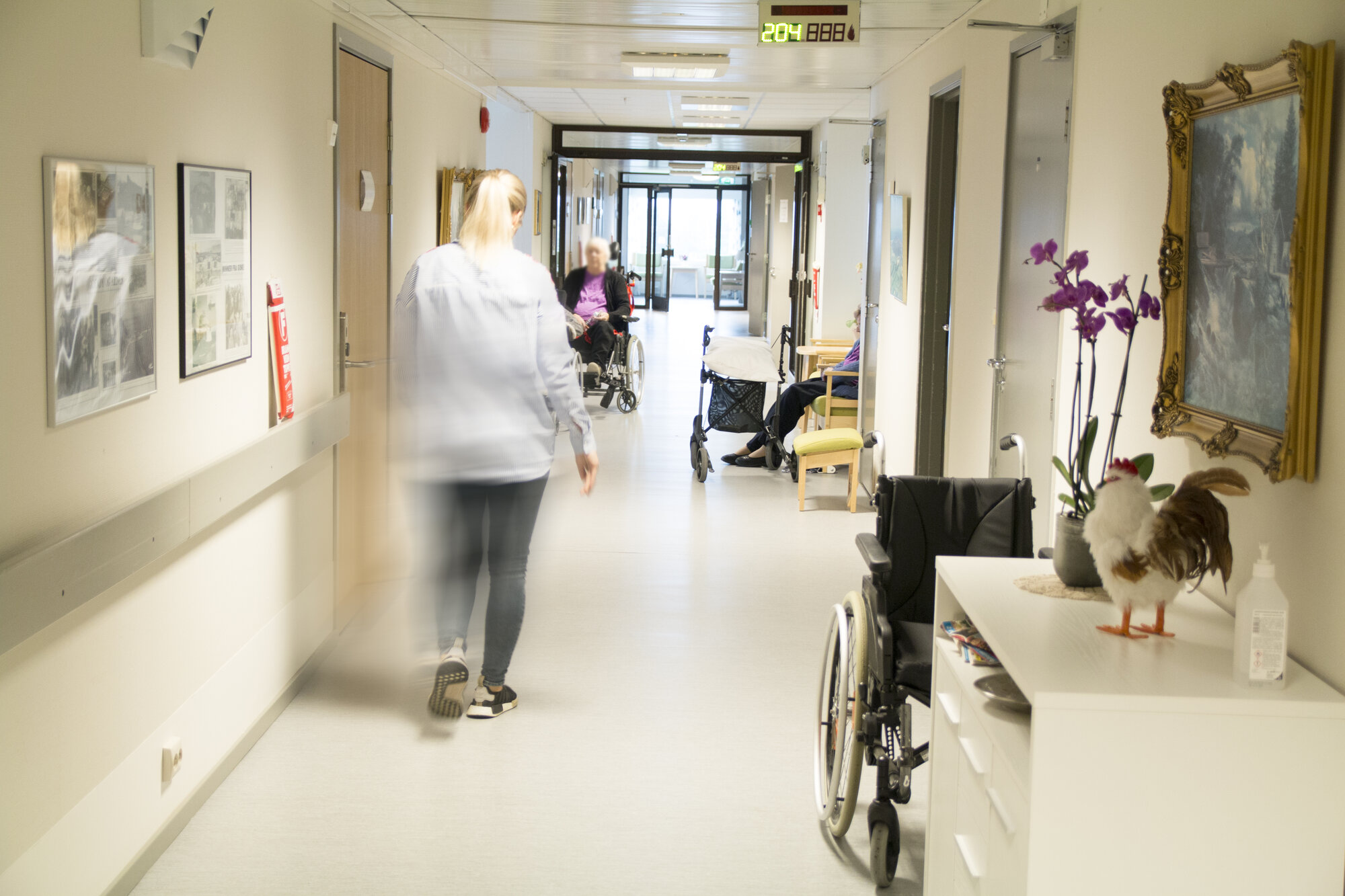 Sykepleier som går nedover en sykehjemskorridor.