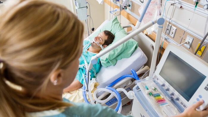 Intensivsykepleier og pasient Bildet viser en intensivsykepleier som overvåker en pasient
