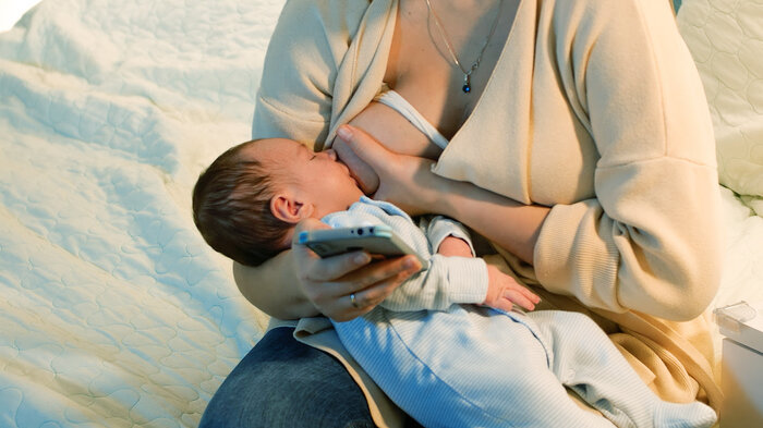 barn som ammes mens mor leser på mobil