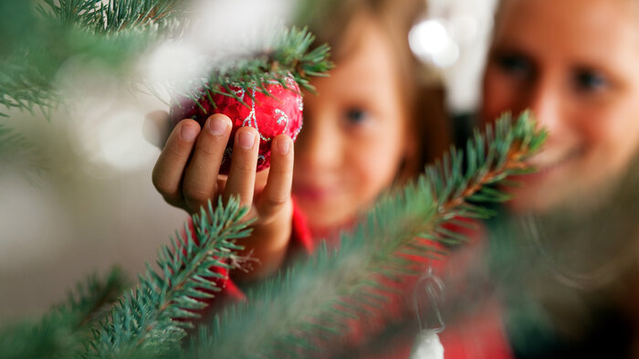 Bildet viser en liten jente og hennes mor som pynter juletre
