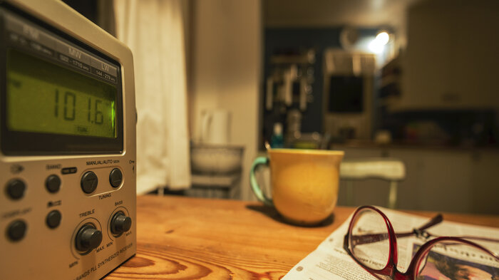 Bildet viser radio, kopp og briller på bord. Illustrasjonsfoto.