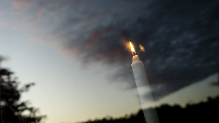 Bildet viser gjenskinnet av et tent lys i et vindu