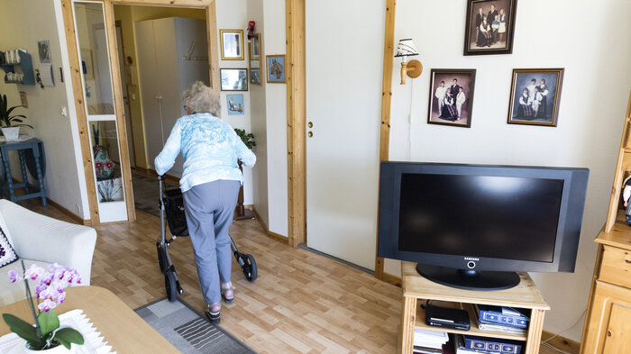 Bildet viser en eldre kvinne med rullator i sitt hjem