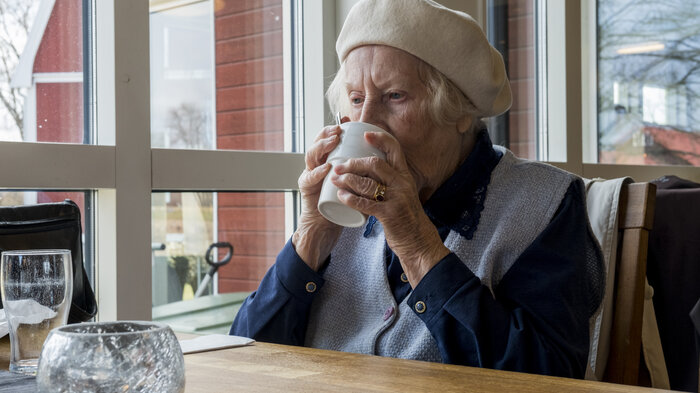 Bildet viser eldre kvinne som drikker av kopp
