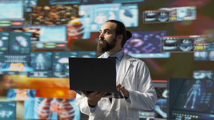 bildet viser sykepleier med pc mot fargerike skjermer