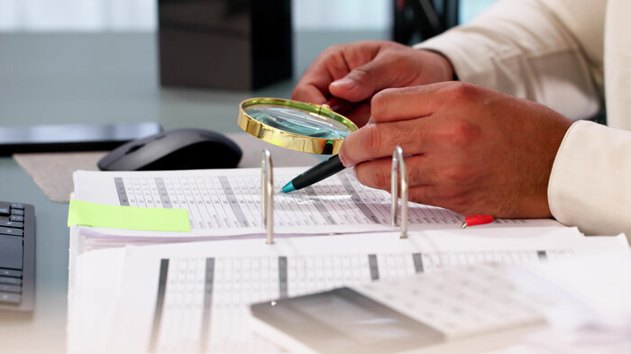 en som gransker et papirdokument bildet viser en som gransker et papirdokument