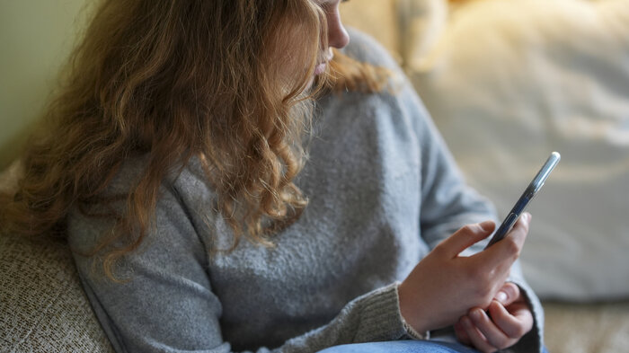 bilde av en jente som leser på mobilen