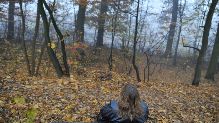 Bilde viser en dame som sitter på en benk med ryggen til Bilde viser en dame som sitter på en benk med ryggen til