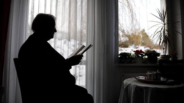 Bilde av eldre person ved kjøkkenbordet