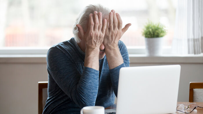 Bildet viser en eldre dame som er sliten foran en datamaskin