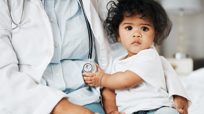 Bildet viser et lite barn som sitter på fanget til et helsepersonell