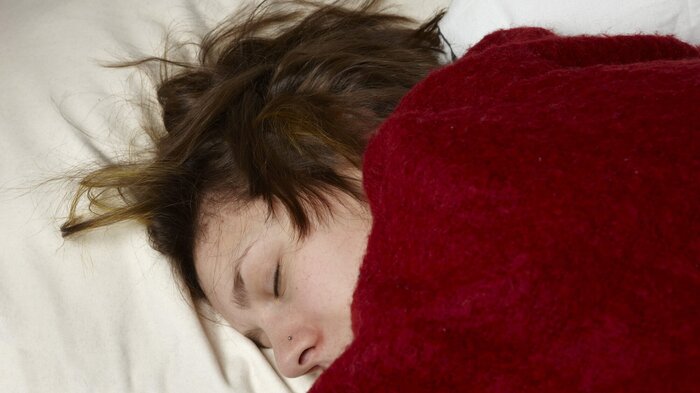 Bildet viser en syk kvinne som ligger i sengen Bildet viser en syk kvinne som ligger i sengen