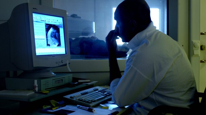 Bildet viser en radiolog som ser på røntgen Bildet viser en radiolog som ser på røntgen