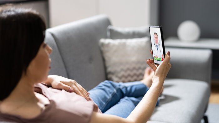 Bilde av person på sofa med mobiltelefon