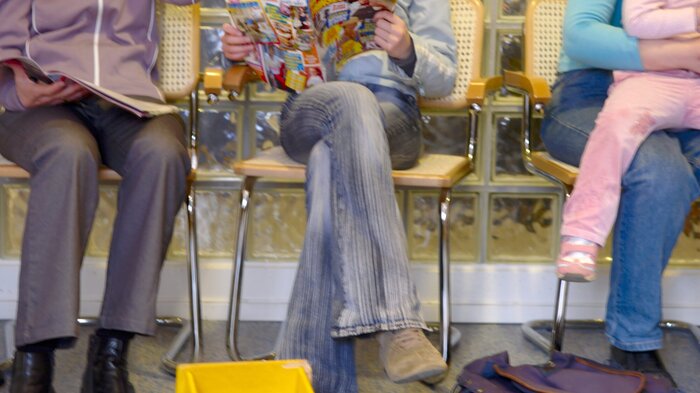 Bildet viser bena til pasienter som sitter på venterom