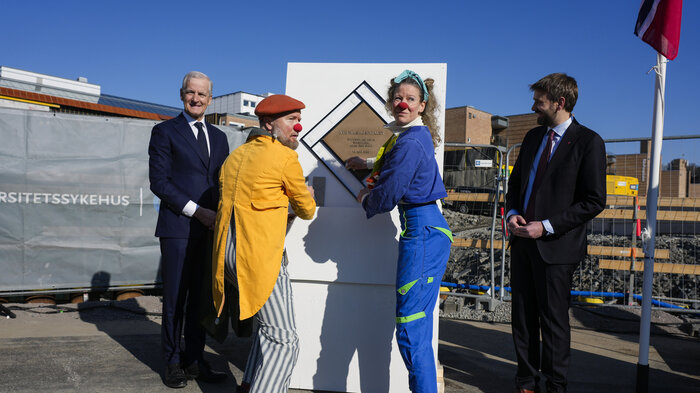 Statsminister Jonas Gahr Støre og helseminister Jan Christian Vestre sammen med sykehusklovnene ved grunnsteinen for det nye Rikshospitalet torsdag.