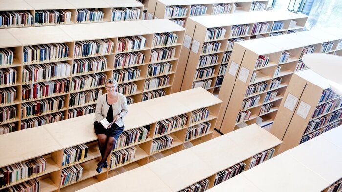 Bildet viser Kristin Heggen som sitter oppå en bokhylle.