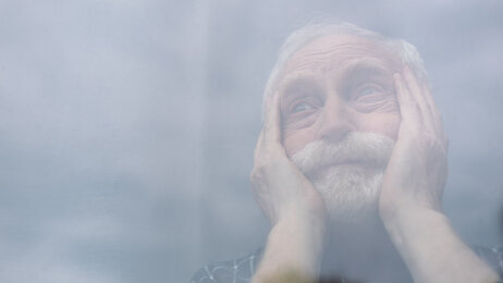 Bildet viser en eldre mann som ser ut i luften mens han hviler hodet i hendene.