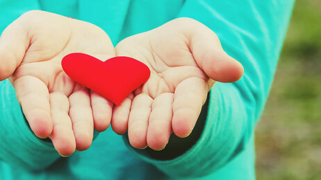 Bildet viser to hender som holder et hjerte