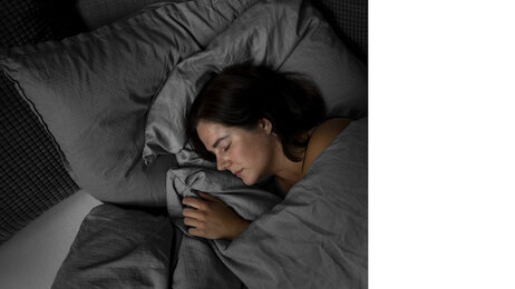 Bildet viser en kvinne som sover i en seng