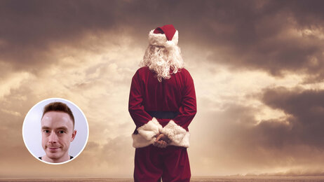 Bildet viser en julenisse med armene på ryggen som ser utover horisonten