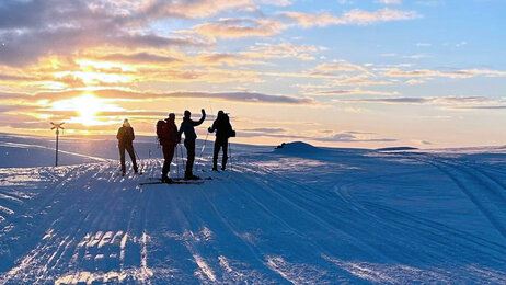 Bildet viser Lill Sverresdatter på ski i solnedgang med sykepleiervenner.