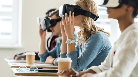 Bildet viser studenter med VR-briller på. De sitter ved sine pulter i et klasserom