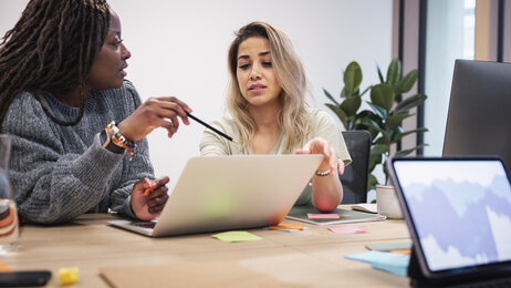 Helsesykepleier og skoleansatt diskuterer Bildet viser to kvinner som sitter og diskuterer foran en PC