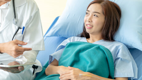 Lege på visitt hos kvinnelig pasient i sykeseng