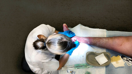 Bildet viser en sykepleier som jobber med et sår.