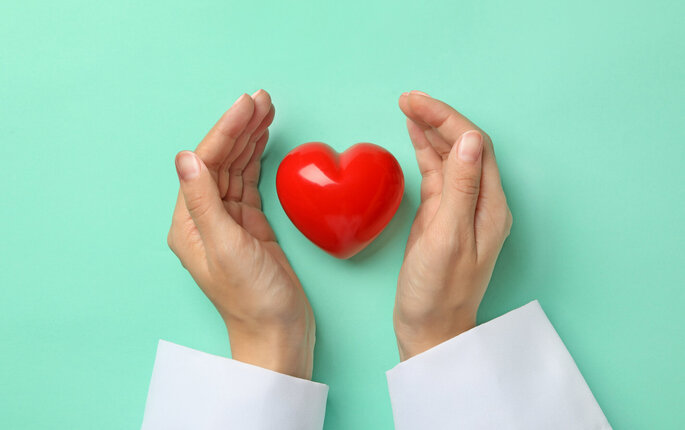 Bildet viser hendene til en sykepleier som holder rundt et hjerte