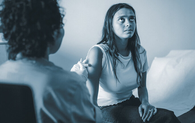 The photo shows a nurse vaccinating a young woman