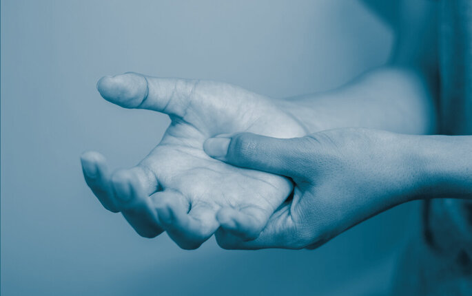 The photo shows two hands, one rubbind the other to signify pain