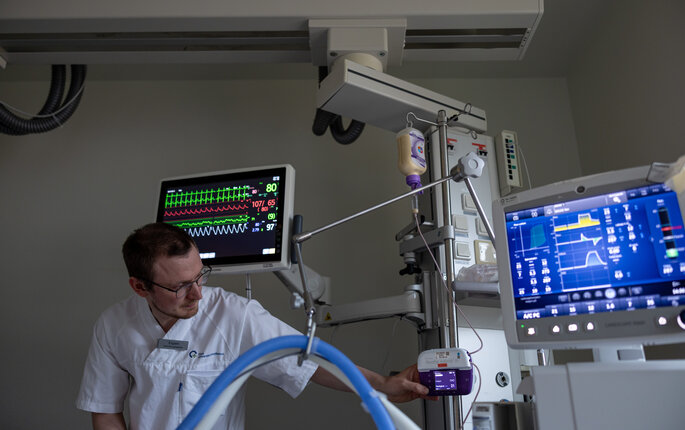 Bildet viser en sykepleier som gjør klart apparat for enteral ernæring på intensiven