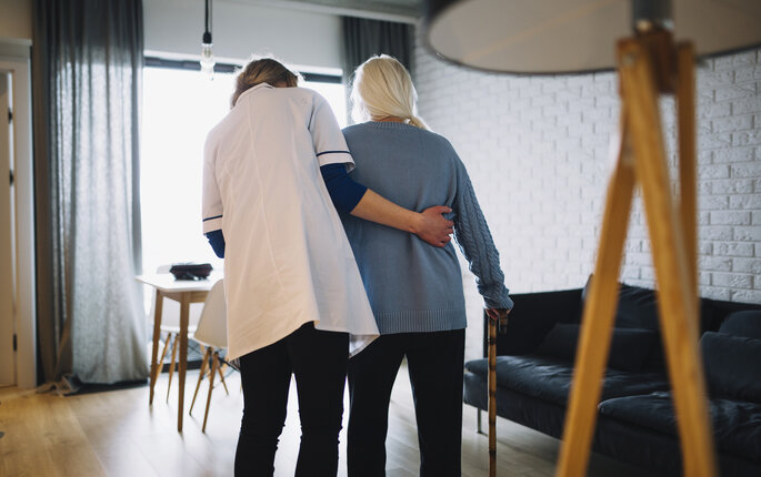 Pleier og eldre Bildet viser en pleier som støtter en eldre pasient