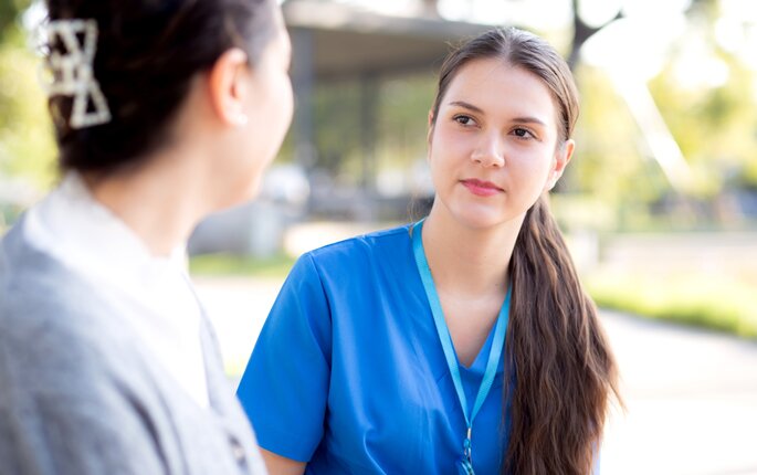 Bildet viser en sykepleier som har en alvorlig samtale med en pasient