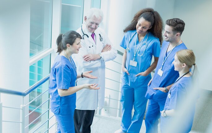 Bildet viser sykepleiere og en lege som snakker sammen i korridoren
