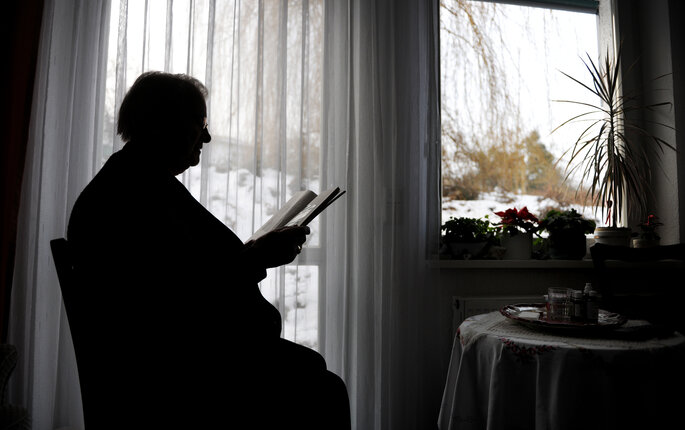 Bilde av eldre person ved kjøkkenbordet